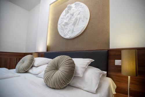 a bed with white pillows and a plate on the wall at Átrium Rooms & Café in Sopron