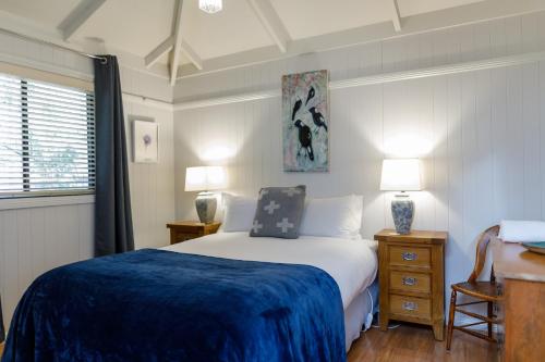 a bedroom with a bed with a blue blanket on it at Bandalong Cottages in Mudgee