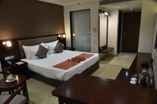 a hotel room with a large bed and a table at Pride Hotel & Convention Centre Indore in Indore