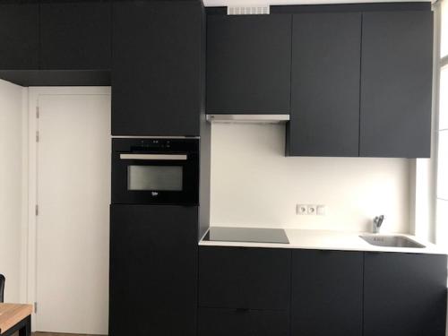 a kitchen with black cabinets and a sink at FLORIDE in Knokke-Heist