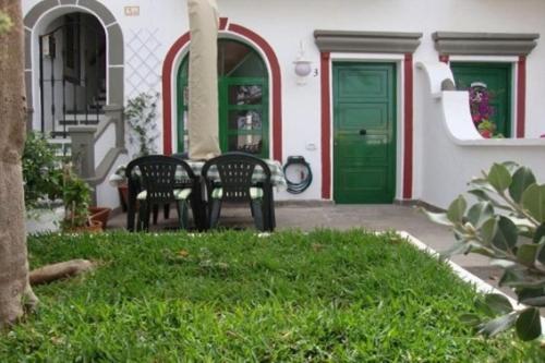 a patio with two chairs and a green door at Little Venice Apartment in Puerto de Mogan in Puerto de Mogán