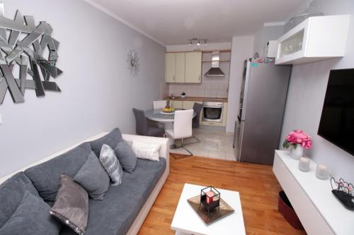 a living room with a gray couch and a kitchen at Apartman *SANJA* Omiš in Omiš