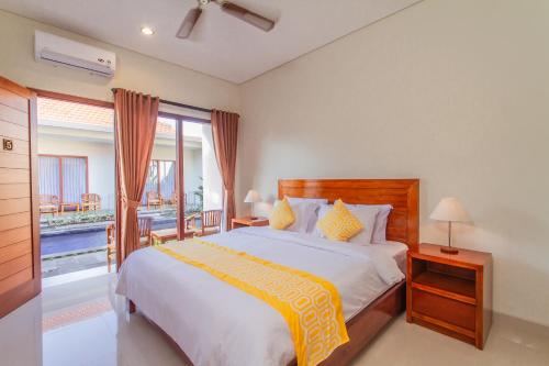 a bedroom with a large bed and a balcony at Cening Ayu Sanur in Sanur