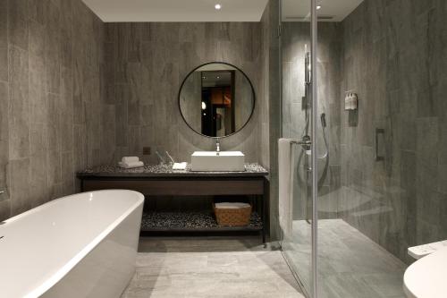 a bathroom with a bath tub and a mirror at COZZI Blu in Zhongli