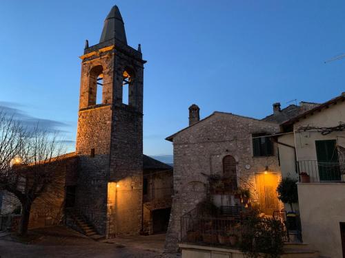 an old stone building with a clock tower at dusk at Casa Della Torre In Borgo Medievale in Stroncone