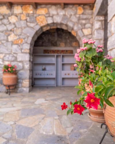 a garage with flowers in front of a stone building at Dryades Villa in Arménoi