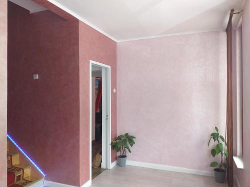 a hallway with pink walls and a dog in a room at Hotel Hobby in Hunedoara