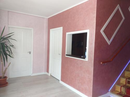 a room with a pink wall with a tv on it at Hotel Hobby in Hunedoara