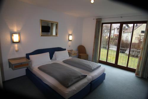 a bedroom with a large bed and a large window at Hotel Zum Forst in Kranzberg