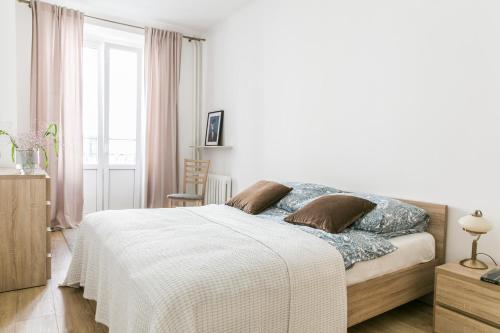 - une chambre blanche avec un lit et une fenêtre dans l'établissement Apartament Poznańska, à Varsovie