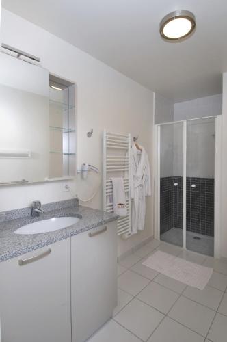 une salle de bain blanche avec un lavabo et une douche dans l'établissement Domitys Les Deux Lacs, à Rumilly