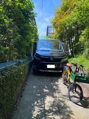 a car parked next to a bike on a road at Kamakura Vacation House in Kamakura
