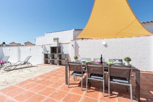 エンプリアブラバにあるApart-rent Casa con piscina Alberes 0005のパティオ(テーブル、椅子、黄色の傘付)