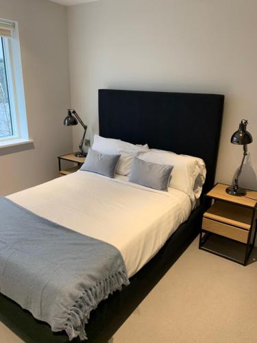 a bedroom with a large bed with a black headboard at Heathrow North Apartments by Charles Hope in Hounslow