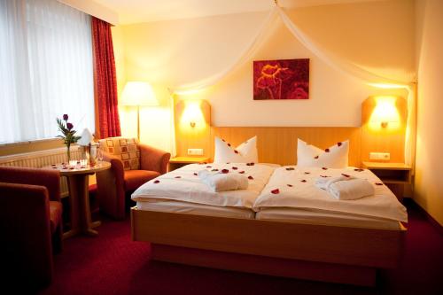 a hotel room with a large bed and a chair at Hotel Englischer Hof in Herzberg am Harz