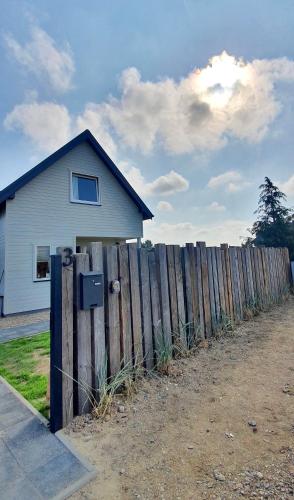 a white house behind a wooden fence with a fence at Baltic Beach House in Rewal
