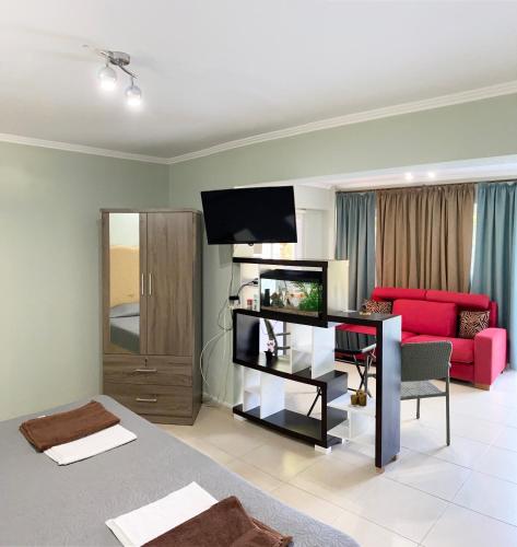 a living room with a red couch and a television at Livia’s Appartments in Paphos