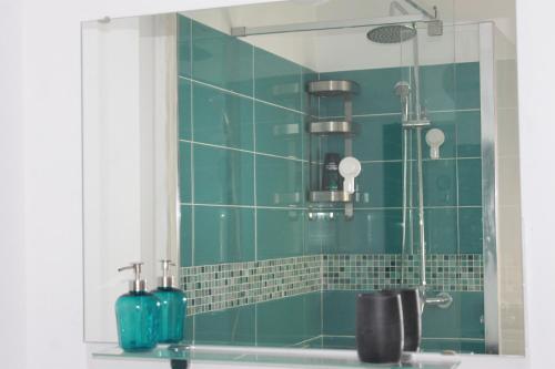 uma casa de banho com azulejos verdes, um chuveiro e um espelho. em STUDIO TURQUOISE Victoria em Bucareste