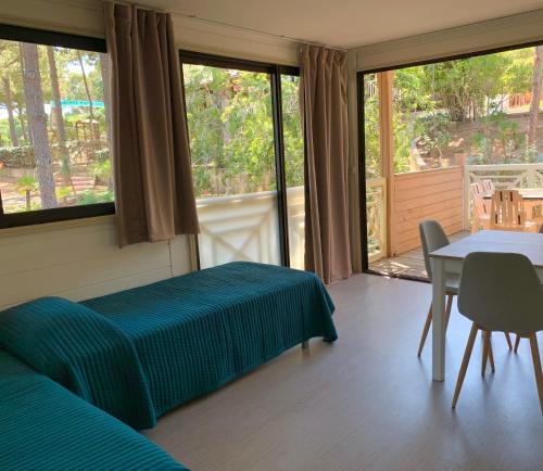 a room with a bed and a table and windows at Résidence Les Pins in Calvi