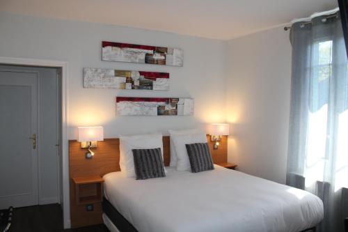 a bedroom with a white bed with two pillows at Logis Hotel De Paris in Jaligny