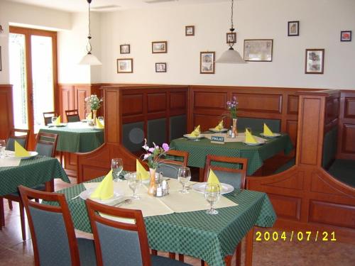 een restaurant met tafels en stoelen met groene tafelkleden bij Várkert Panzió in Miskolc