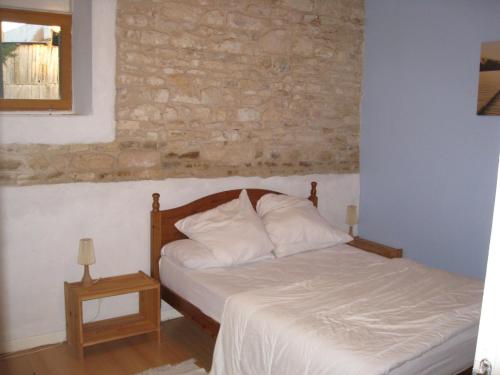 1 dormitorio con cama y pared de ladrillo en La Grange, en Vanzay
