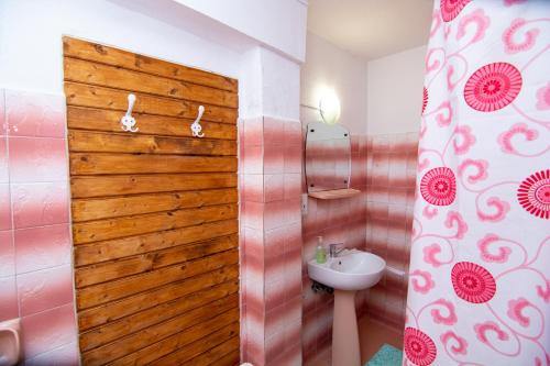 ein Badezimmer mit einer Holztür und einem Waschbecken in der Unterkunft Pension Csomád in Băile Tuşnad