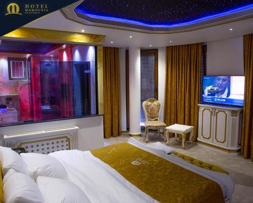 a bedroom with a large bed and a flat screen tv at Hotel Mamounia Boutique in Prishtinë