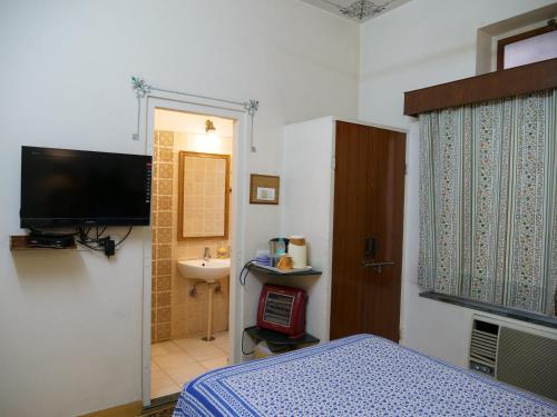 a bedroom with a bed and a sink and a television at Hotel Arya Niwas in Jaipur