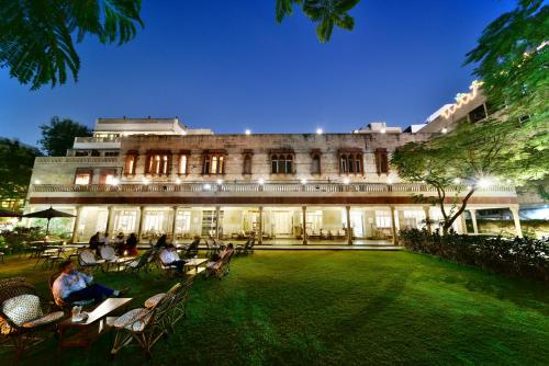 a building with people sitting in chairs in front of it at Hotel Arya Niwas in Jaipur