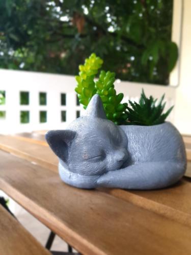a figurine of a gray cat sleeping on a table at ฮักเคียงโขง HUG Khieng Khong Nongkhai Hostel in Nong Khai