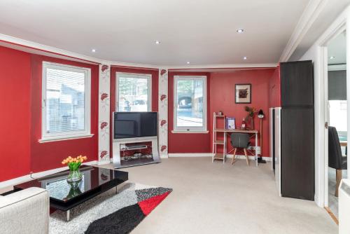 a living room with red walls and a flat screen tv at Historic Location, Private Parking, Ground Floor Luxury Flat in Aberdeen