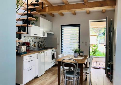 une cuisine avec une table et des chaises et une cuisine avec des armoires blanches dans l'établissement Maison duplex, avec terrasse dans Strasbourg, à Strasbourg