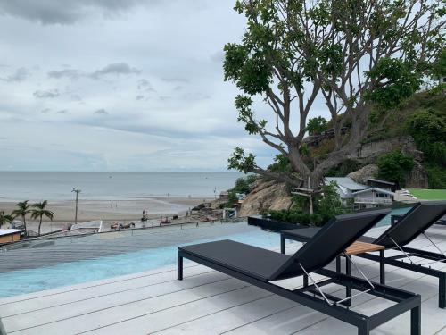 a pool with two lounge chairs and a beach at Santorini Khao Takiab Huahin Beach Front in Hua Hin