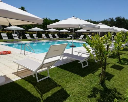 un grupo de sillas y sombrillas junto a una piscina en Masseria Carrozzi en Melendugno