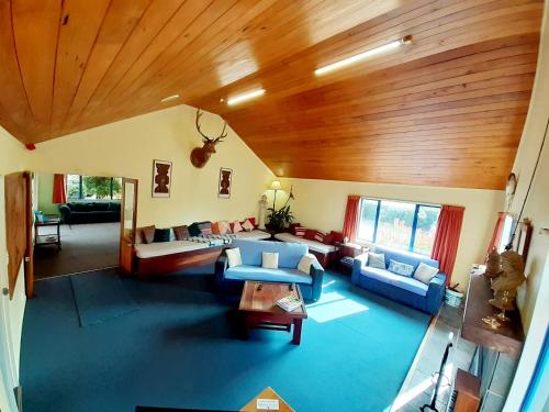 a living room with blue couches and a wooden ceiling at Tongariro River Retreat in Turangi
