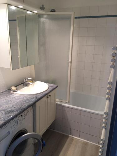 une salle de bain avec un lavabo et une machine à laver dans l'établissement Face à la mer à Cabourg, à Cabourg