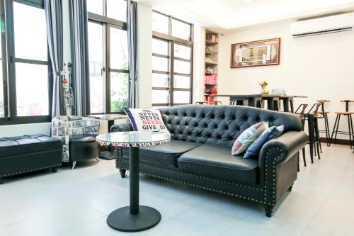 a living room with a black leather couch and a table at 十二籃民宿 in Magong