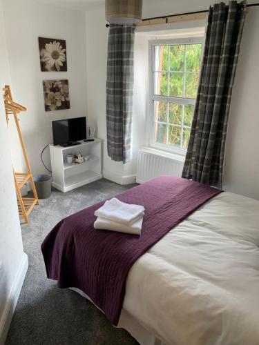 a bedroom with a bed with a purple blanket and a window at DOVENBY SHIP in Tallentire