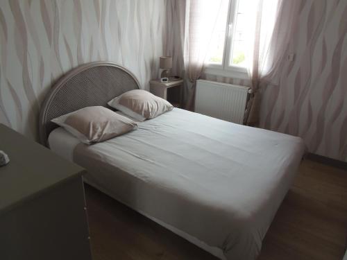 ein Bett mit zwei Kissen in einem Zimmer mit einem Fenster in der Unterkunft maison de vacances in Grandcamp-Maisy