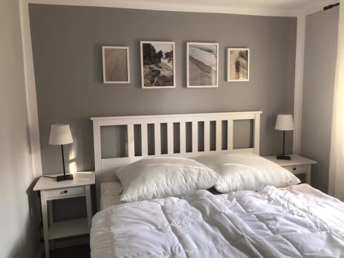 - une chambre avec un lit blanc et trois photos sur le mur dans l'établissement Ferienwohnung Familie Manthei, à Boitin Resdorf
