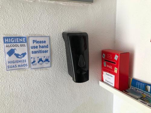 a black object is on a wall next to signs at Fonte da Telha Beach Hostel in Costa da Caparica