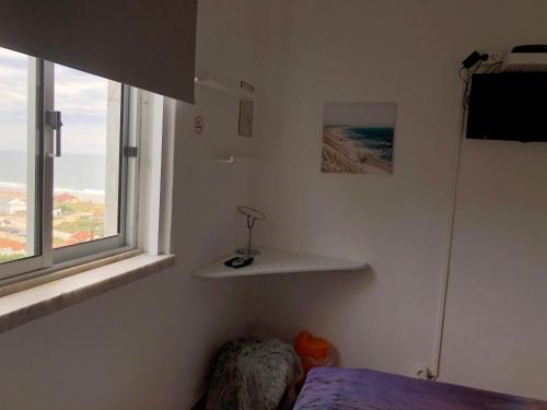 Schlafzimmer mit einem Bett und einem Fenster in der Unterkunft Fonte da Telha Beach Hostel in Costa da Caparica