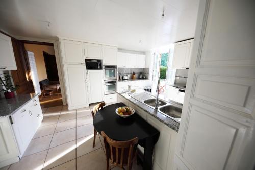 a white kitchen with a black table and chairs at Gite Logis des Fontaines in Raon-lʼÉtape