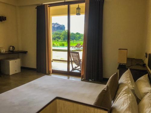 a living room with a couch and a sliding glass door at Lankapura Heritage in Sigiriya