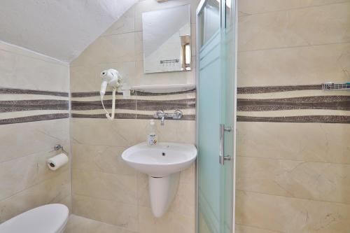 ein Badezimmer mit einem Waschbecken, einem WC und einem Spiegel in der Unterkunft Santosa Pension in Kaş