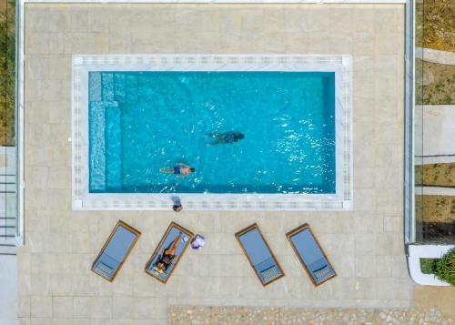 an overhead view of a swimming pool with people in the water at CORFOS BLUE MYKONOS in Ornos
