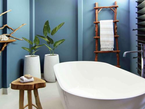 a bathroom with a white tub and three plants at Elements Of Byron in Byron Bay