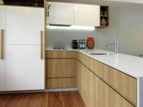 a kitchen with a white refrigerator and wooden cabinets at Elements Of Byron in Byron Bay