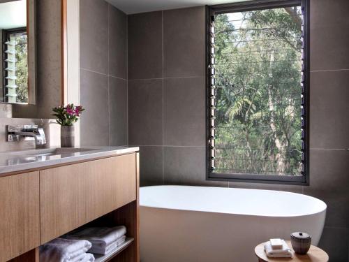 a bath tub in a bathroom with a window at Elements Of Byron in Byron Bay